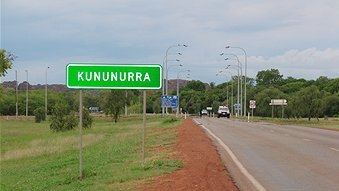 A  sign that reads 'Kununurra' by an outback road.