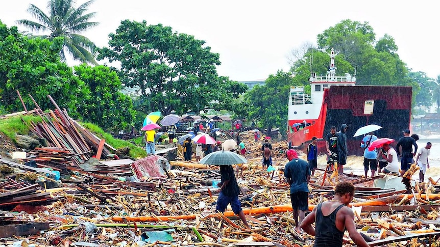 Locals walk through debris left after days of heavy rain in the Solomon Islands.