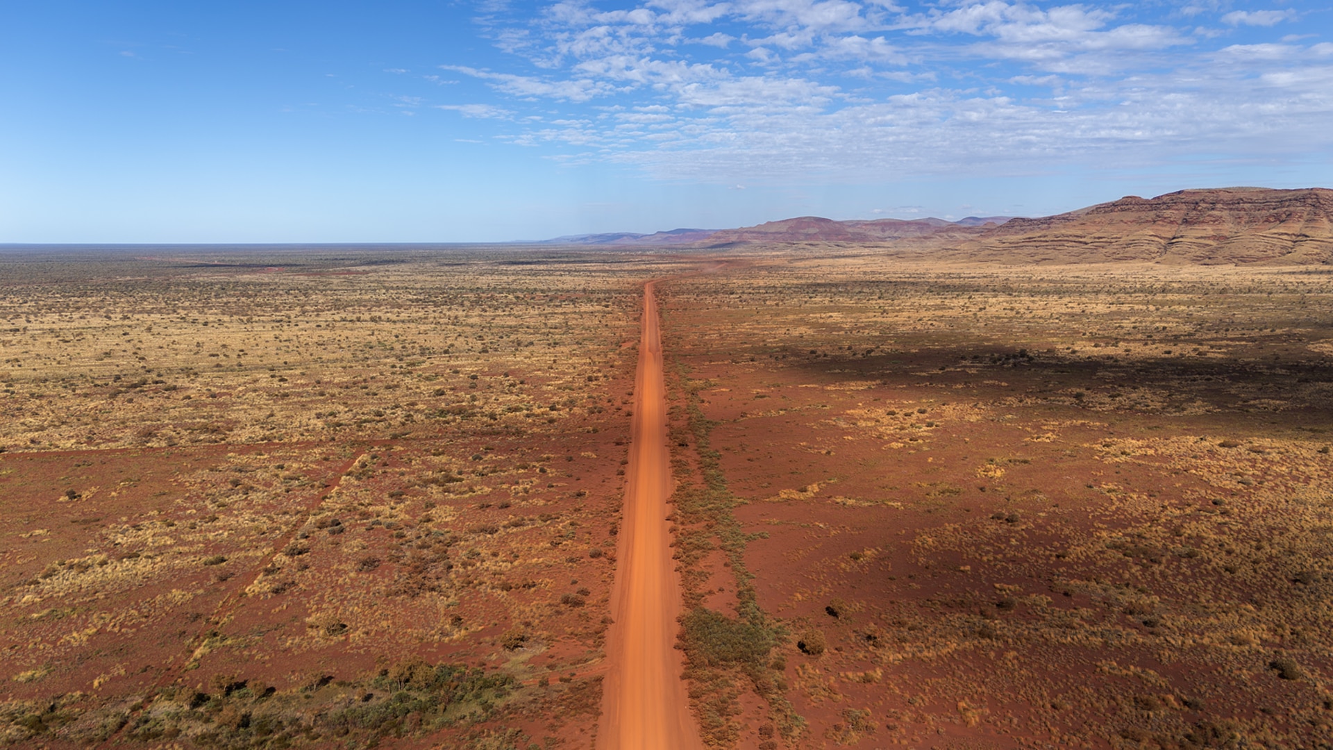 An unsealed road runs off into the distance in WA's Pilbara.