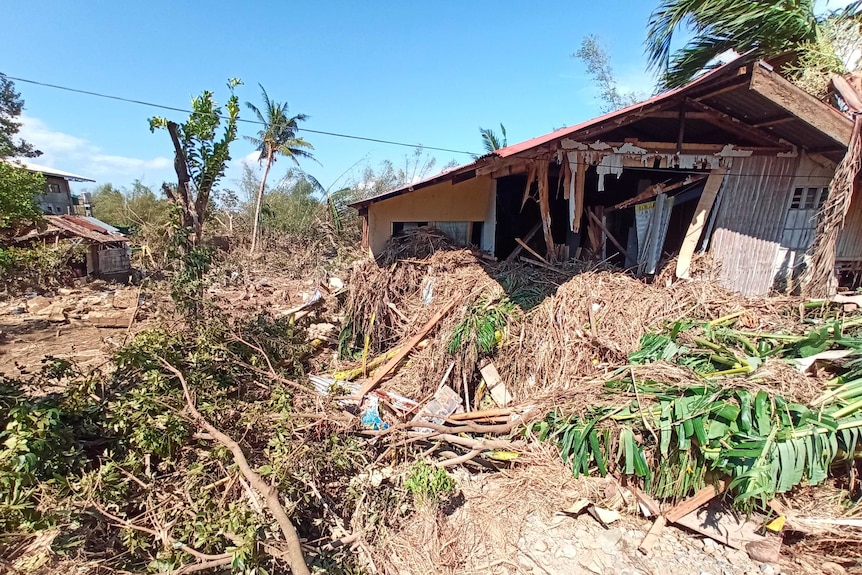 A house lays in ruins covered by debris.