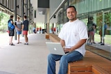 Carlos Garcea sits on a wooden bench outside the education building at James Cook University Townsville
