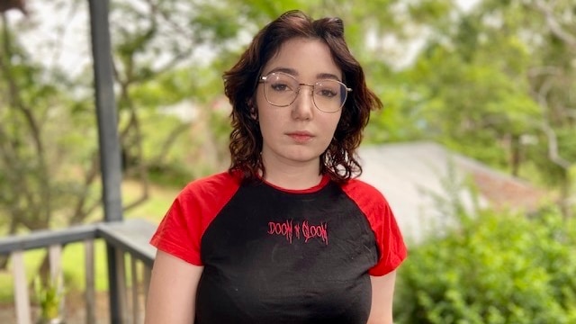 a young woman in glasses with a t-shirt which says doom and gloom