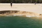 People stand near landslip into the sea at Inskip Point on Queensland's Cooloola Coast.