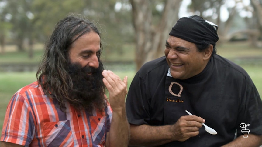 Two men outdoors, facing each other and laughing