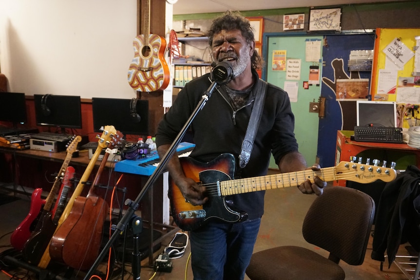 A man playing a guitar and singing 