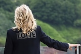 First Lady Jill Biden wears a black jacket with the word "Love" in bold letters printed across the back.