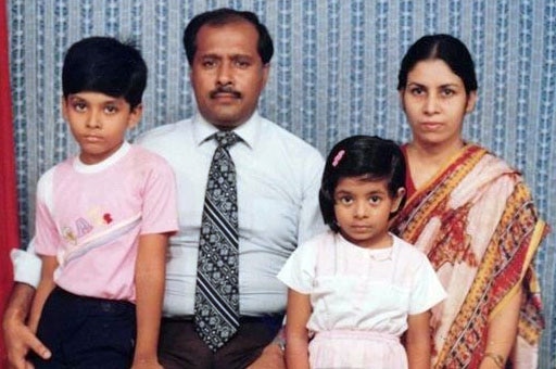A family sits facing the camera in front of a blue background.