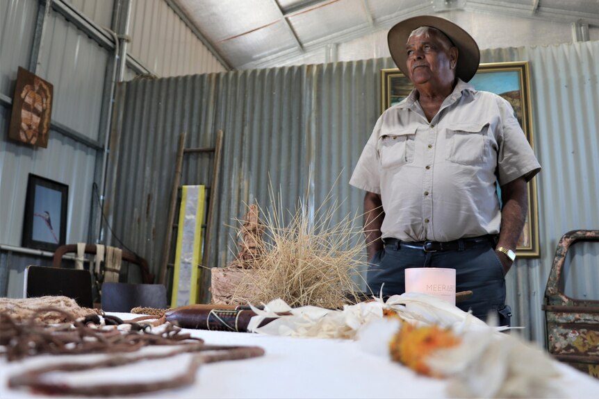 A ranger stands next to a table of artifacts. 