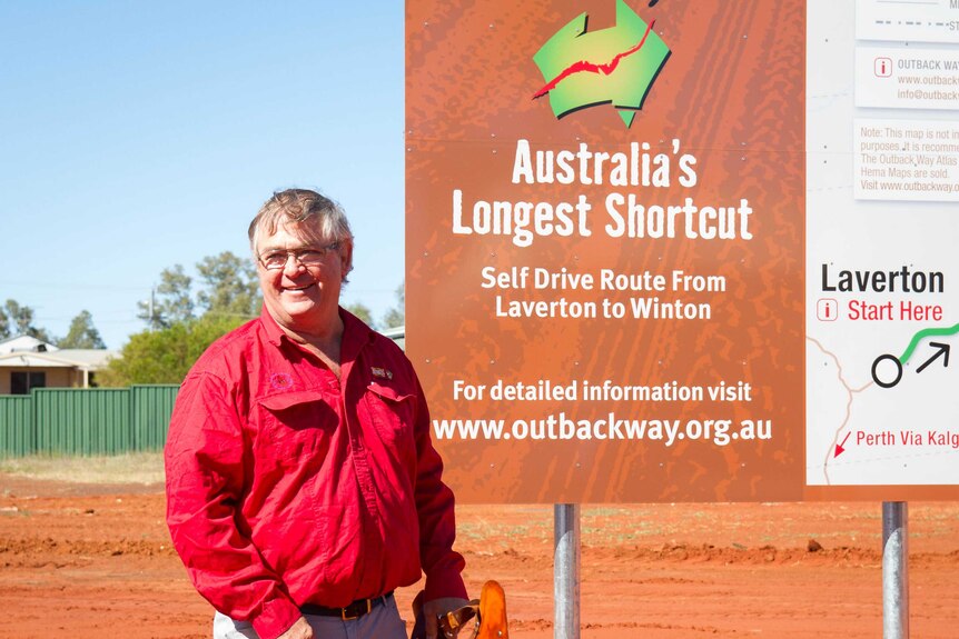 Le président du comté, Patrick Hill, debout devant le tout nouveau panneau Outback Way à Laverton.