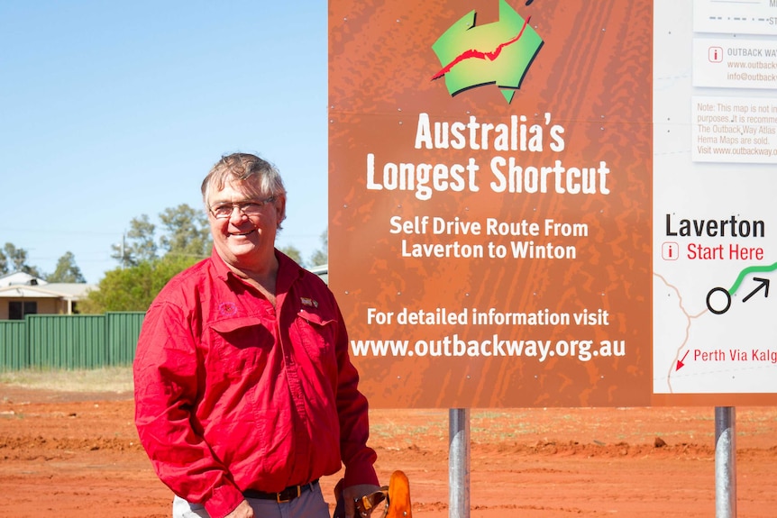 Le président du comté, Patrick Hill, debout devant le tout nouveau panneau Outback Way à Laverton.