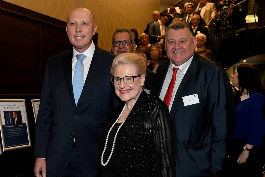 Two men and a woman smile for photographs