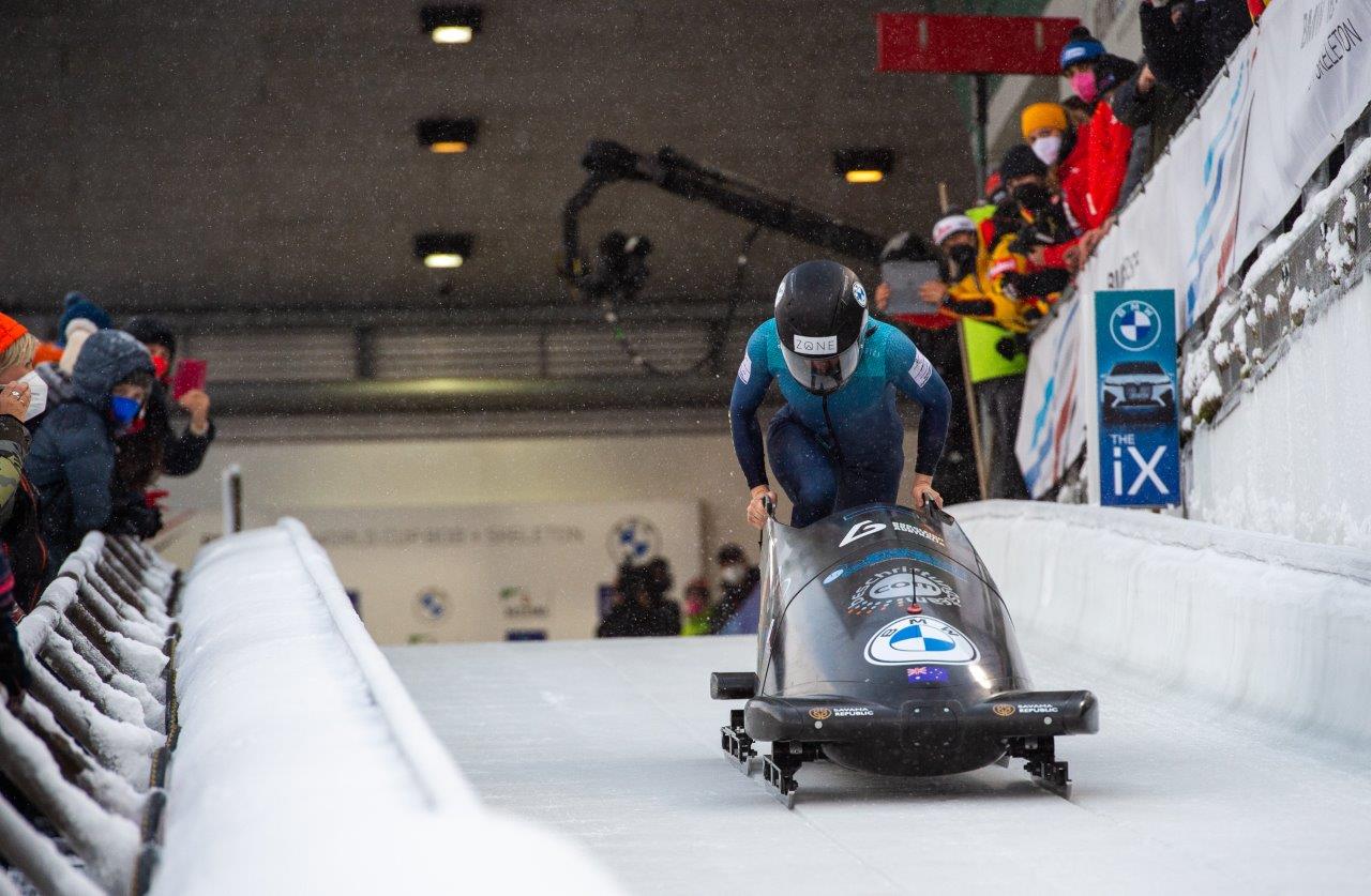 Bree Walker runs behind a monobobsled wearing a helmet
