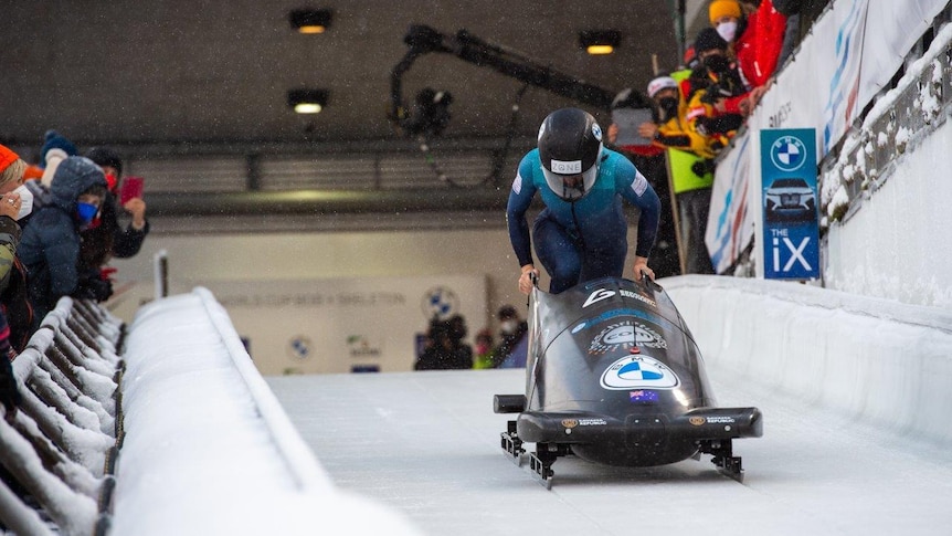 Bree Walker runs behind a monobobsled wearing a helmet