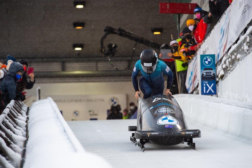 Bree Walker runs behind a monobobsled wearing a helmet