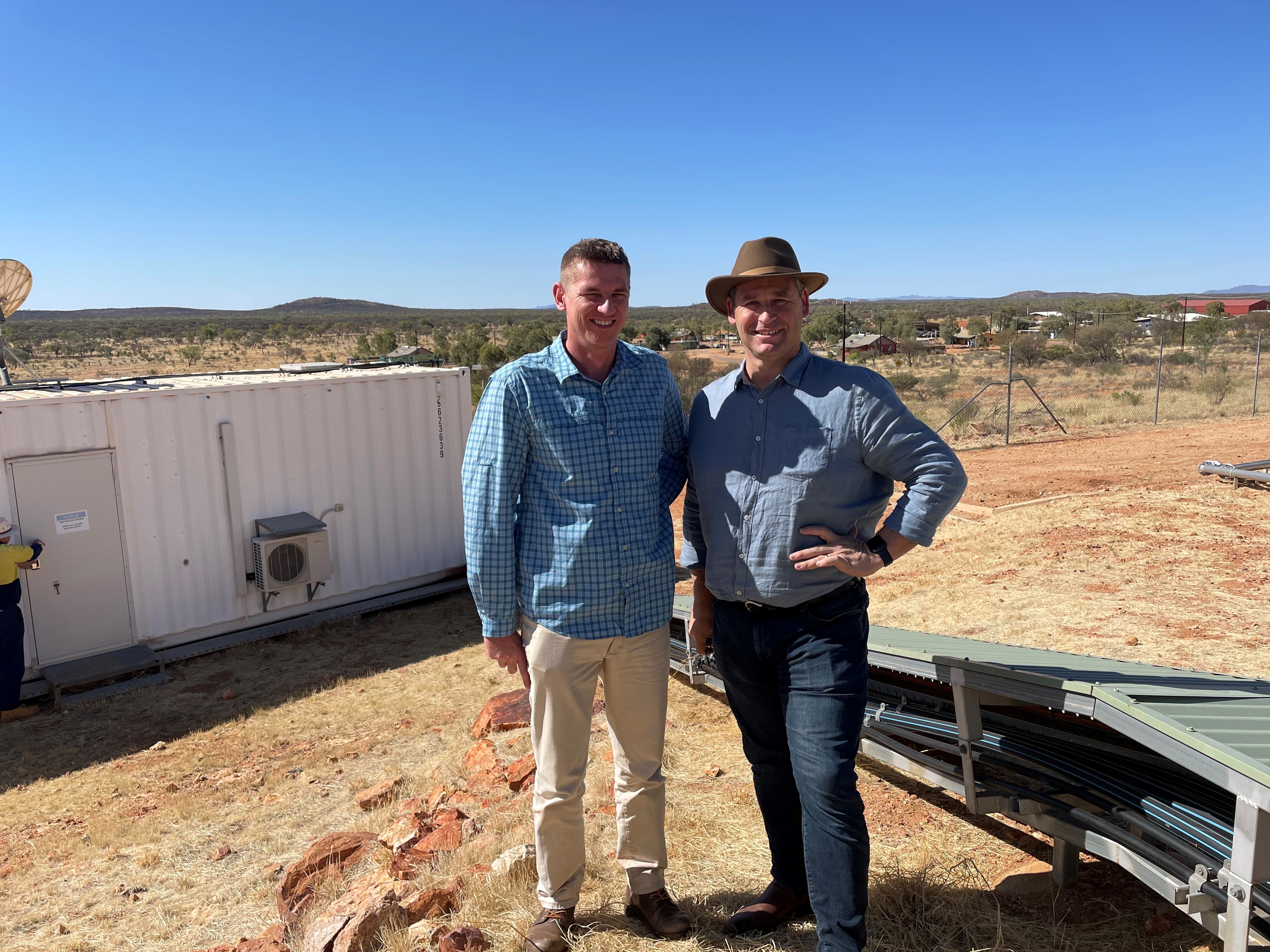 Two men stand in a desert community. 