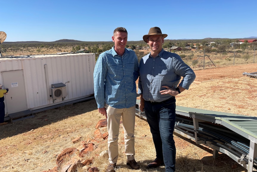 Two men stand in a desert community. 