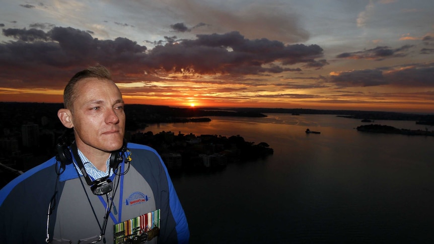 Man atop Sydney Harbour bridge at sunrise.