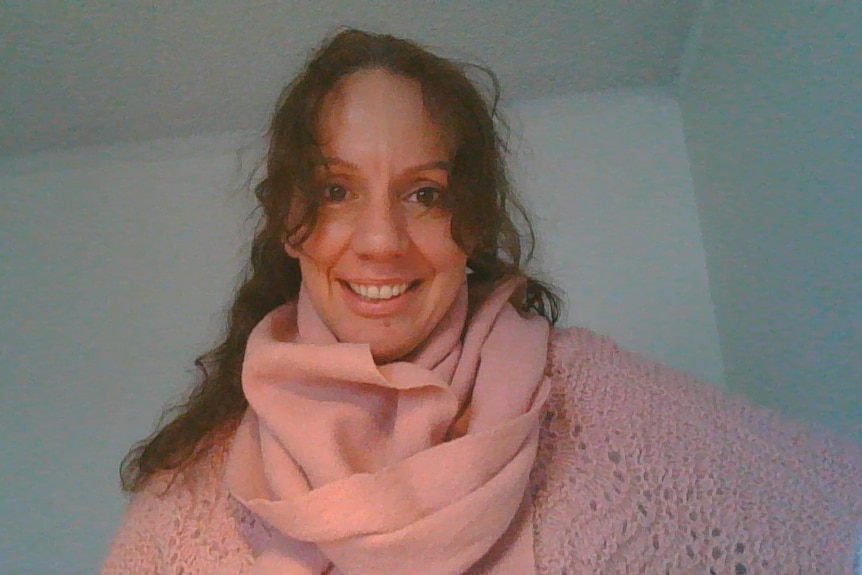 Gwen wears a pink scarf and smiles at the camera
