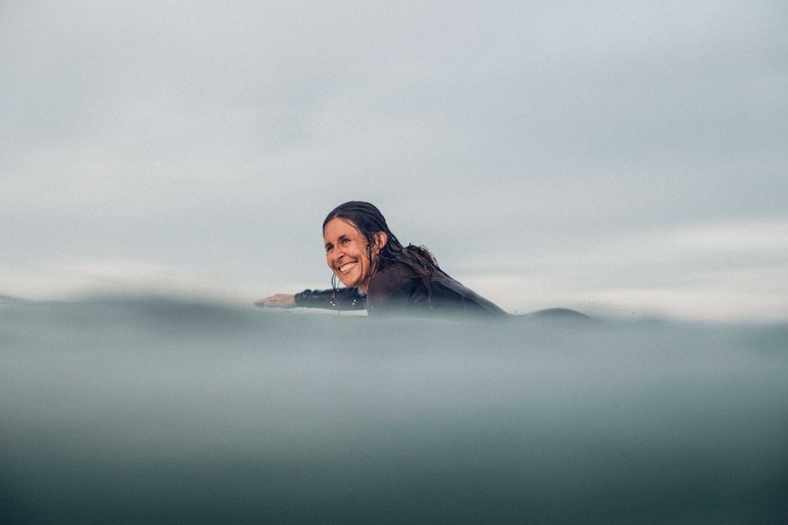 A woman wearing a wetsuit surfing in the water.