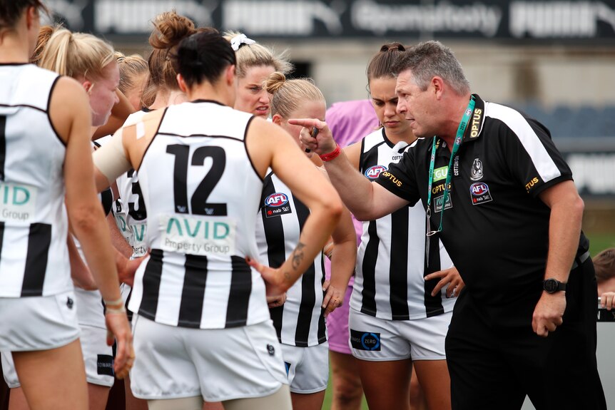 Steve Symonds, senior coach of the Magpies, addresses his player. He is pointing at the group who look disappointed