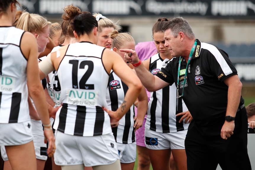 Steve Symonds, senior coach of the Magpies, addresses his player. He is pointing at the group who look disappointed