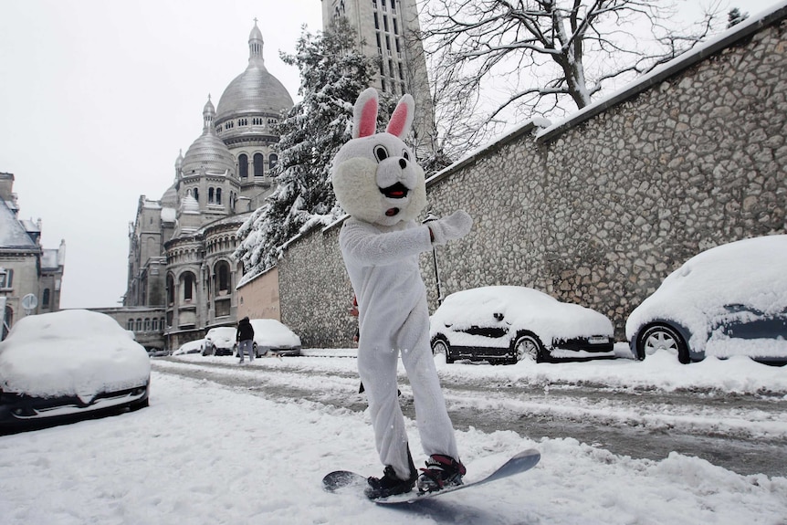 A man wearing a rabbit mask rides his snowboard down the Montmartre hill in Paris.