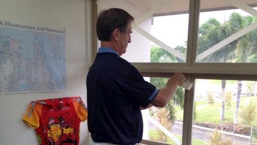 Cook Shire Mayor Peter Scott tapes his office windows in Cooktown ahead of the arrival of Cyclone Ita.