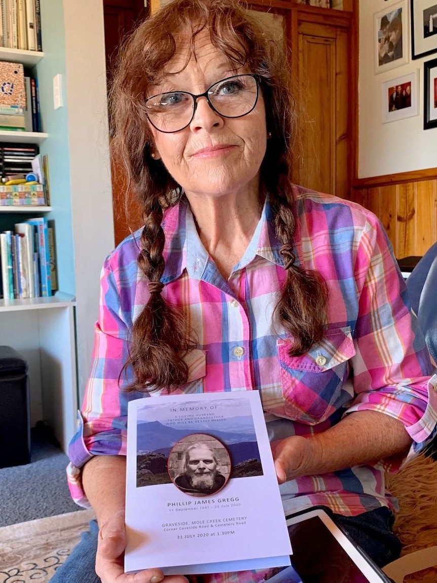 A woman with plaits and wearing glasses sits on her couch