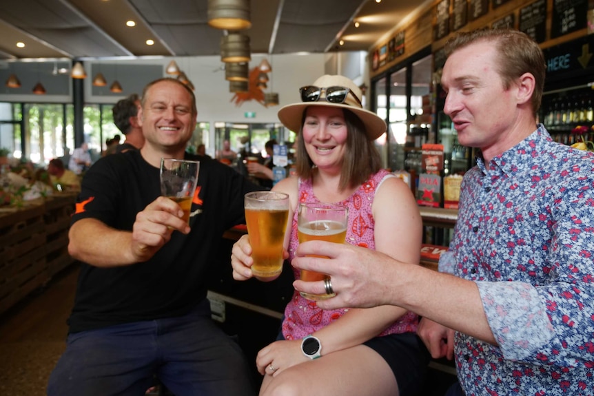 Three people holding beer in brewery