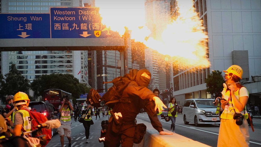A Hong Kong protesters wearing all black throws a firebomb on a road