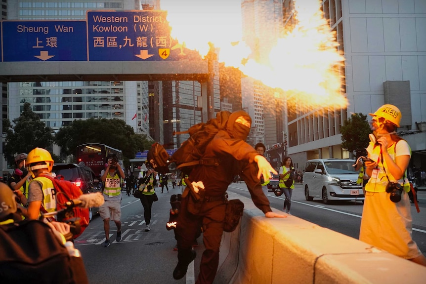 A Hong Kong protesters wearing all black throws a firebomb on a road