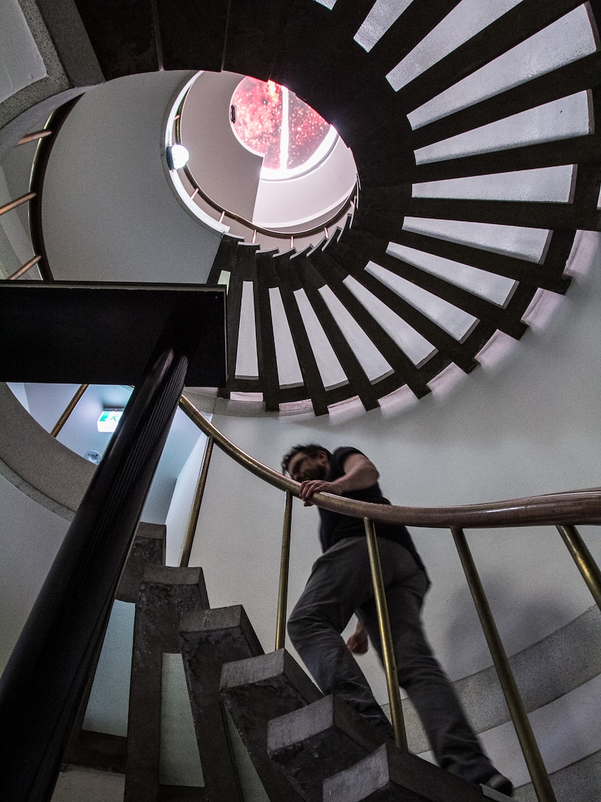 Man walking up a helical staircase.