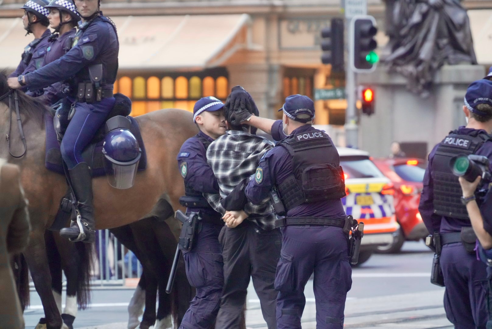 La policía detiene a un hombre en la calle, con agentes de la policía montada a su lado