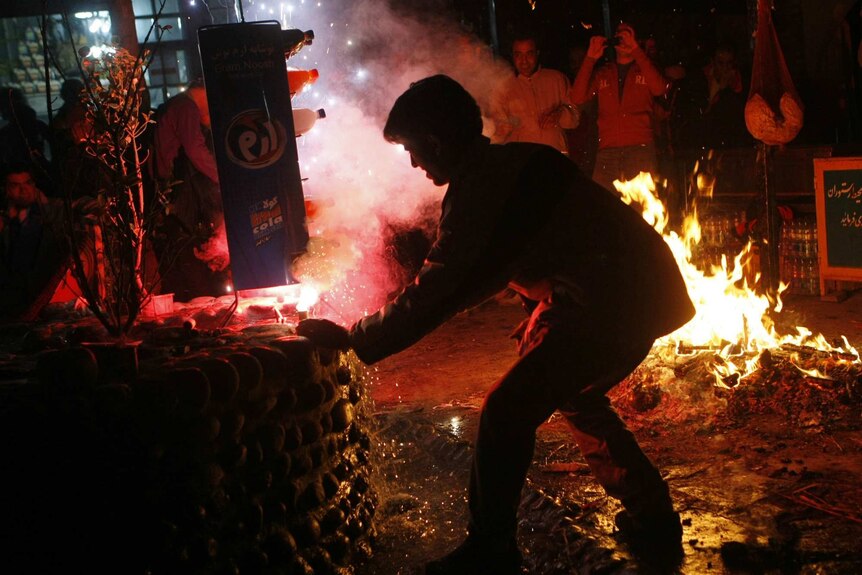 An Iranian man lights a firecracker