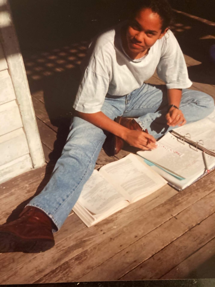 Corowa sitting on ground with binder and books open.