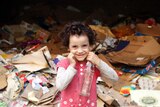 A young girl smiles as she stands among rubbish at a garbage dump in Cairo.