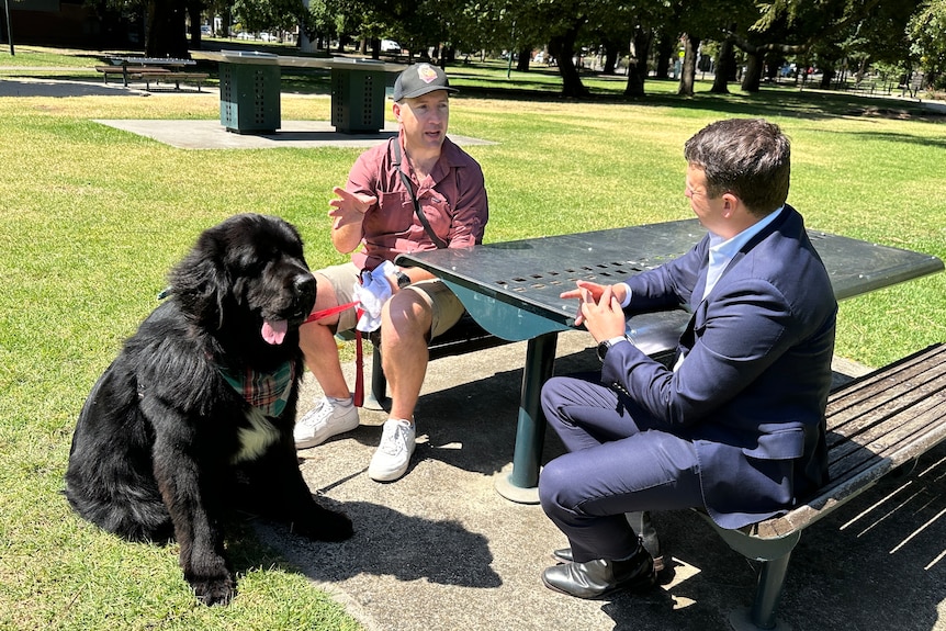Detective Sergeant Peter Romanis, pictured with ABC reporter Mike Lorigan. They are sitting at a picnic table in a park.