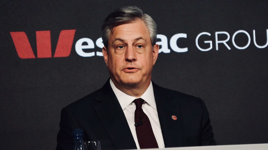 Medium close up of Westpac chief executive Brian Hartzer wearing a black suit, seated in front of a sign reading Westpac Group