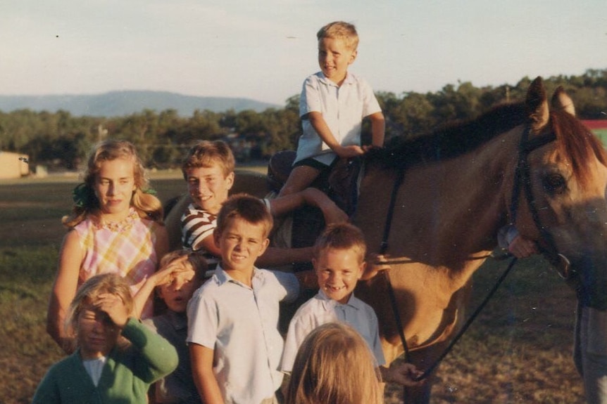 Children including young English migrant Paul Gilmore surround a horse.