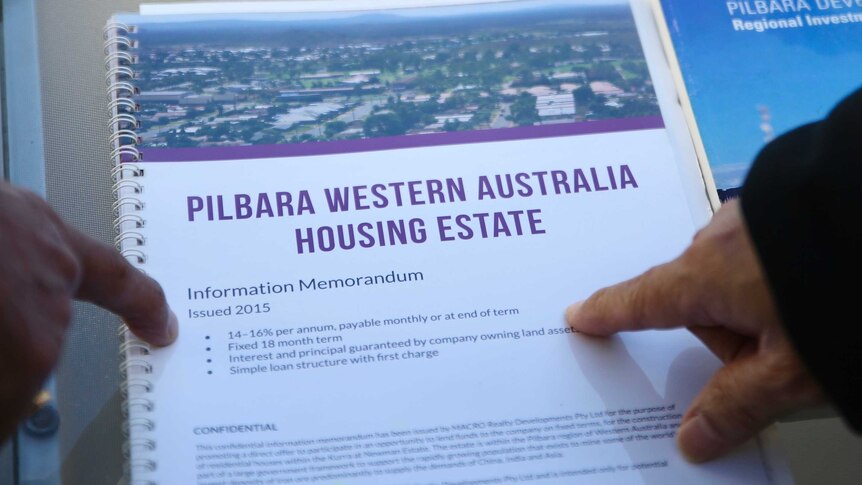 Fingers pointing at a brochure for a property investment scheme.