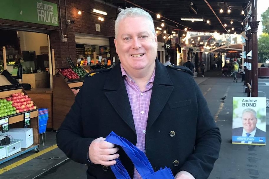 Andrew Bond hands out shopping bags at South Melbourne Market.