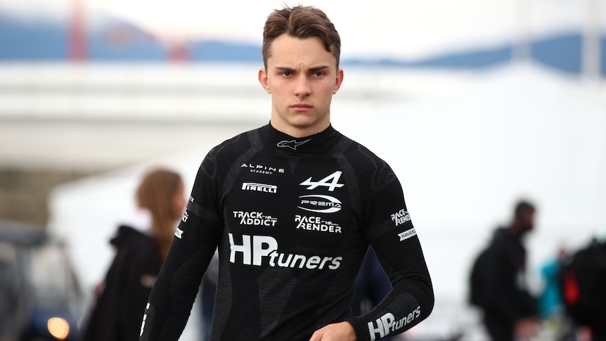 An Australian Formula 2 driver walks with his helmet off in Sochi.