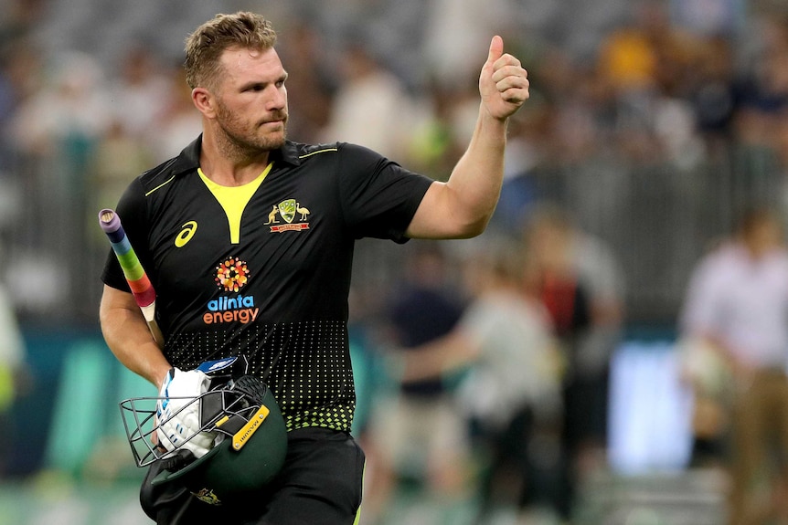 Aaron Finch gives the crowd a thumbs up while carrying his bat, helmet and gloves.