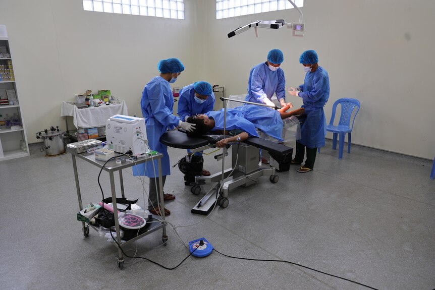 A doctor and nurses around a surgery bed and patient.