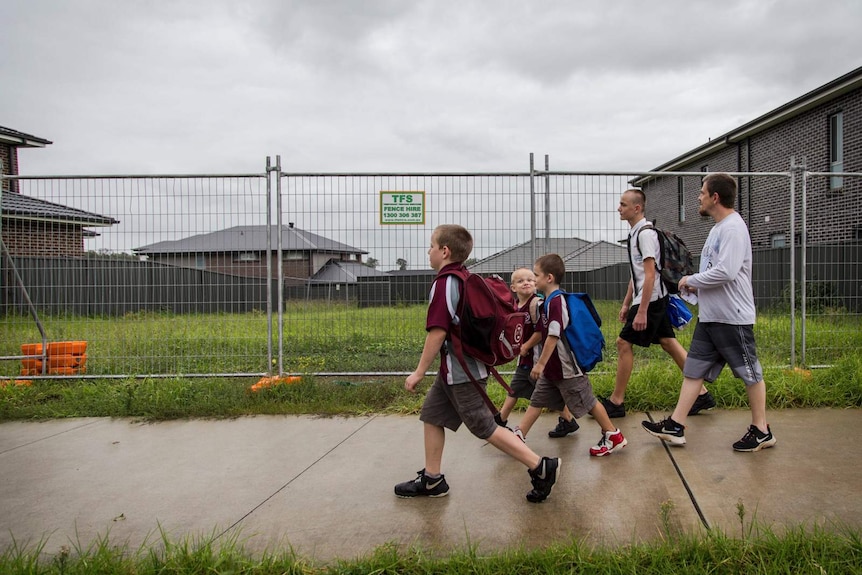 a father and his four sons walking past an undeveloped lot