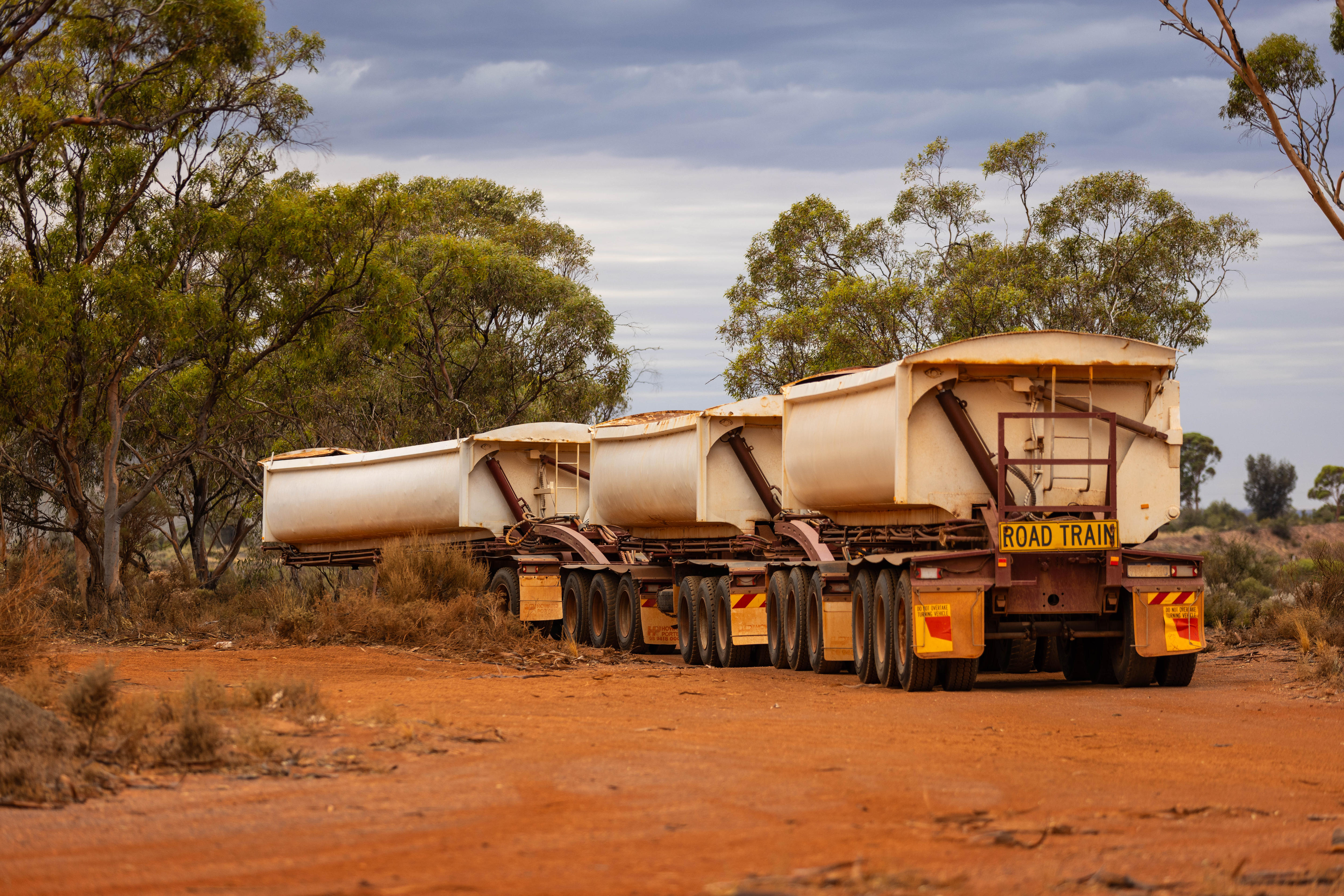 Remolque para un tren de carretera estacionado en un camino de tierra en el matorral.