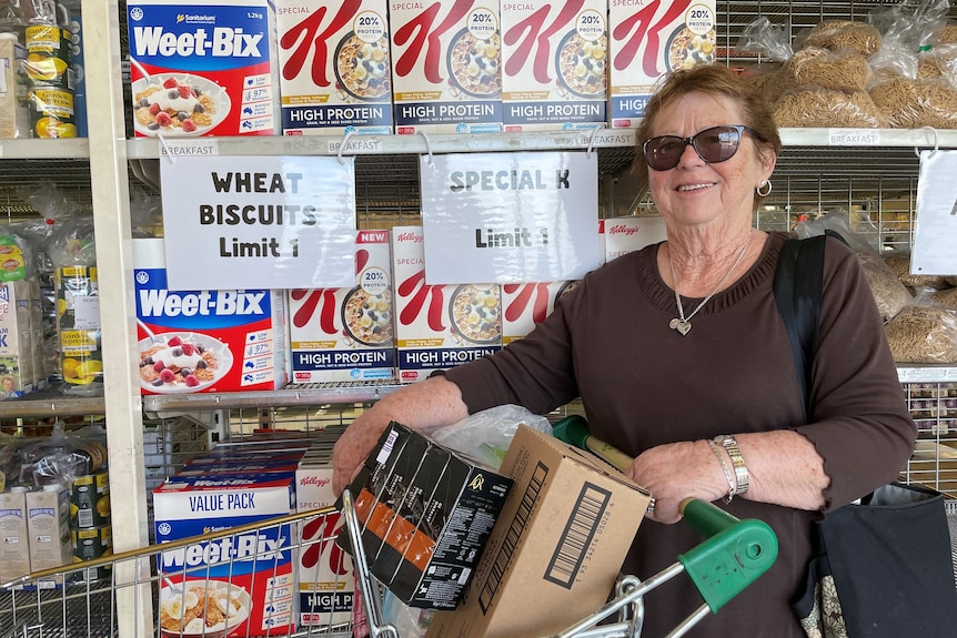 A lady smiling with sunglasses on standing in front of cereal in the grocery aisle