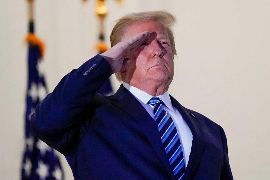 Donald Trump holds a salute on the White House balcony after returning from his COVID-19 hospitalisation