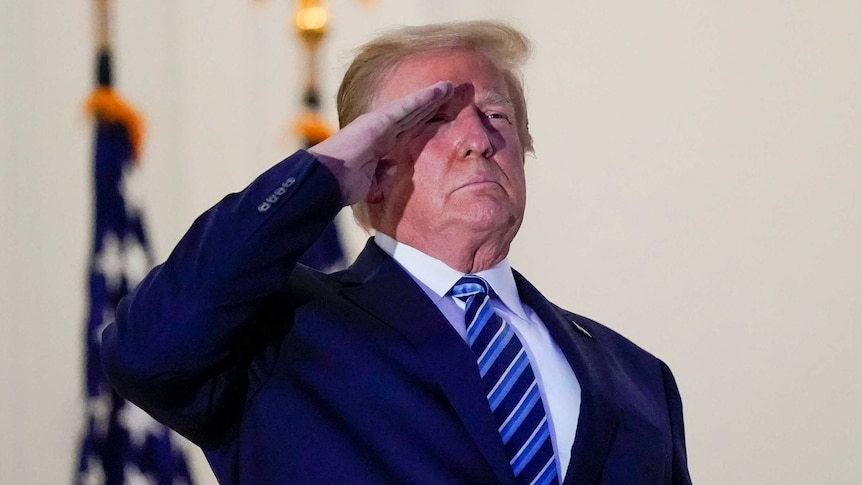 Donald Trump holds a salute on the White House balcony after returning from his COVID-19 hospitalisation