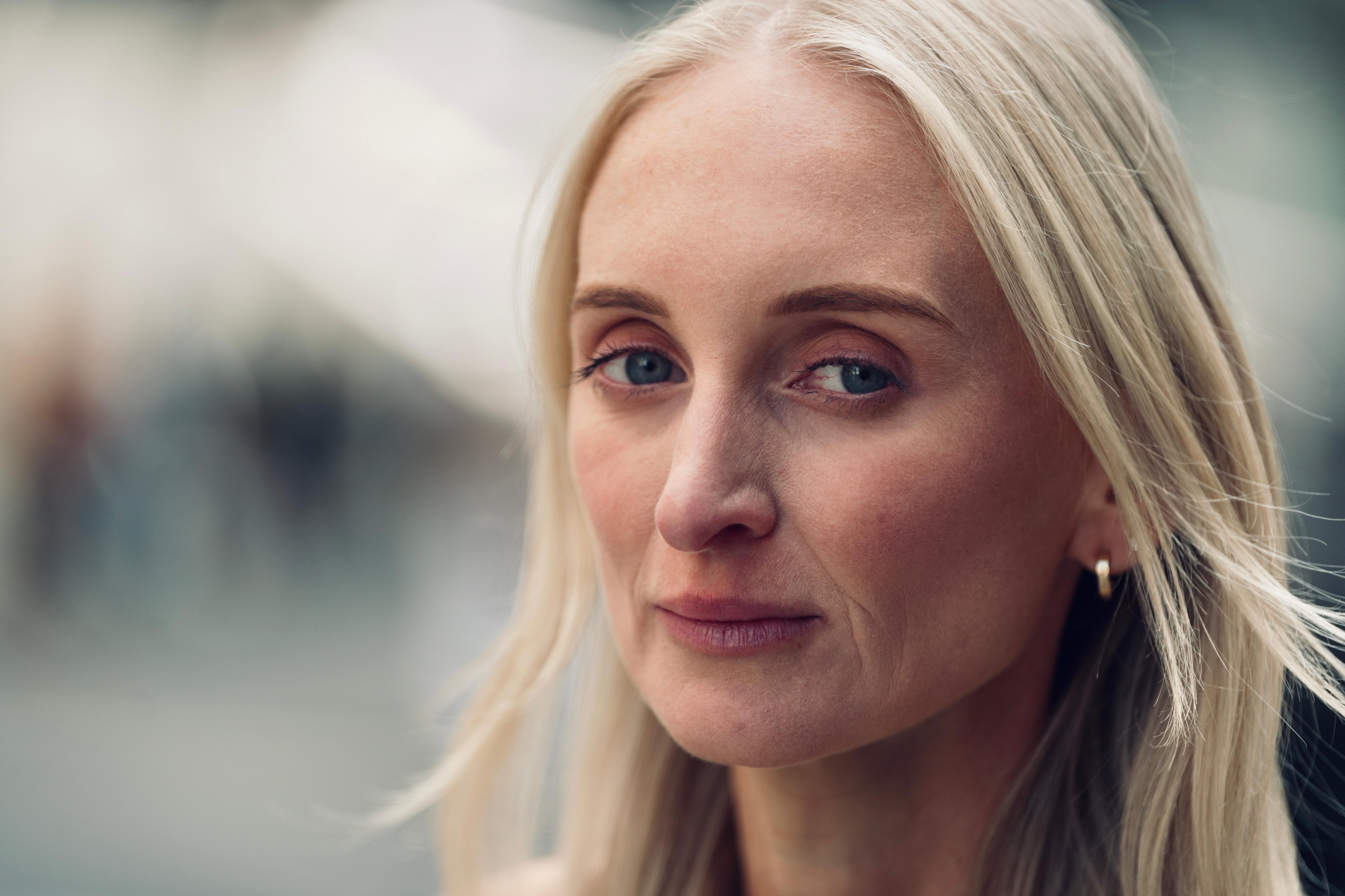 A close-up photo of Samantha Bouffler, who has blonde hair, blue eyes, and is wearing gold earrings